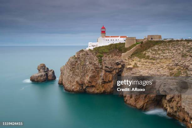 algarve amazing seascape. continental europe's most south-western point, sagres, portugal. landscape of the lighthouse and cliffs at cape st. vincent at sunset. - headland stock-fotos und bilder