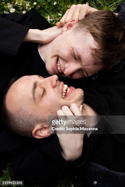 A young LGBT couple lying in the grass hugging and laughing