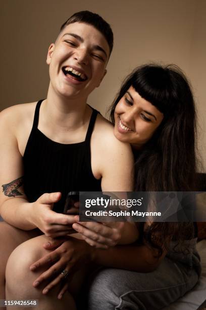 A young LGBT couple laughing at a mobile phone