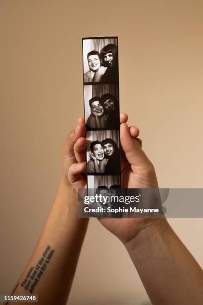 a young couple holding up a photograph - fotobooth stock-fotos und bilder