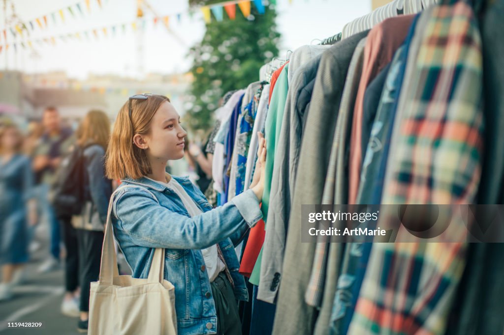 Junges Mädchen wählt Kleidung in einem Second-Hand-Markt im Sommer, Null-Abfall-Konzept