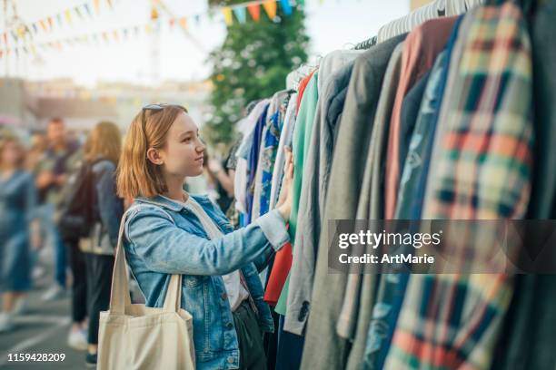 jeune fille choisissant des vêtements dans un marché d'occasion en été, concept zéro déchet - clothing photos et images de collection