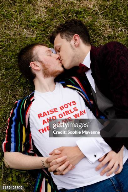 A young LGBT couple lying in the grass and kissing