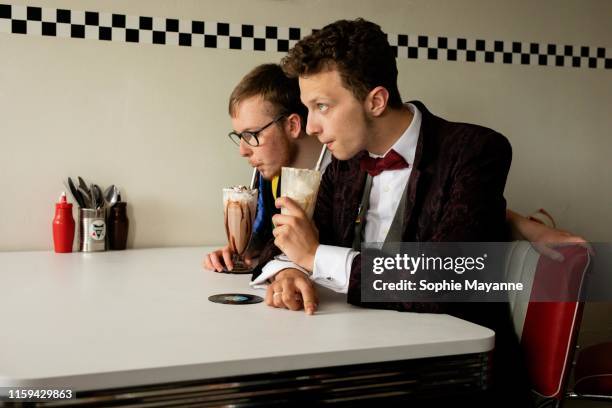 A young LGBT couple drinking milkshake in a diner