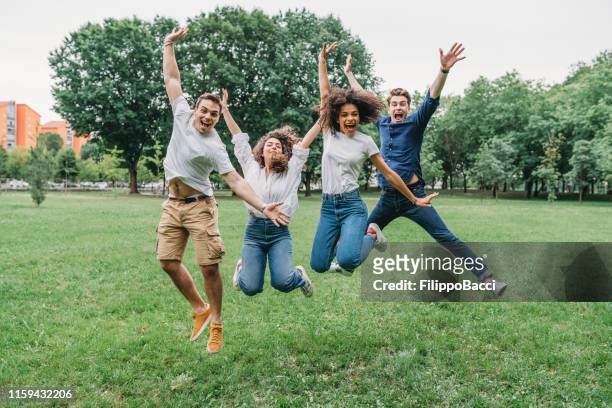 amigos saltando juntos en el parque - campus party fotografías e imágenes de stock