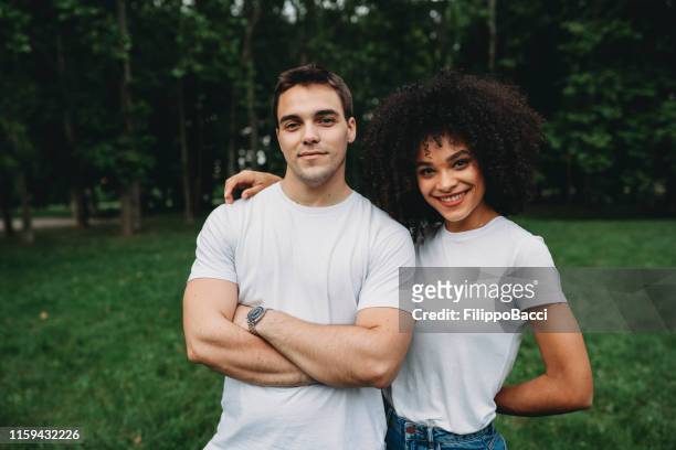 retrato de una pareja de jóvenes adultos con una camiseta blanca al aire libre - camisa blanca fotografías e imágenes de stock