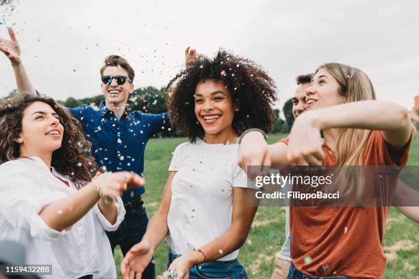 group of friends having fun together at the park with confetti - generation z diversity stock pictures, royalty-free photos & images