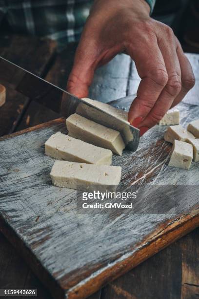 schneiden von tofu auf holzschneidebrett - tofu stock-fotos und bilder
