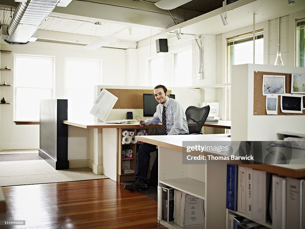 Businessman sitting at desk in office smiling