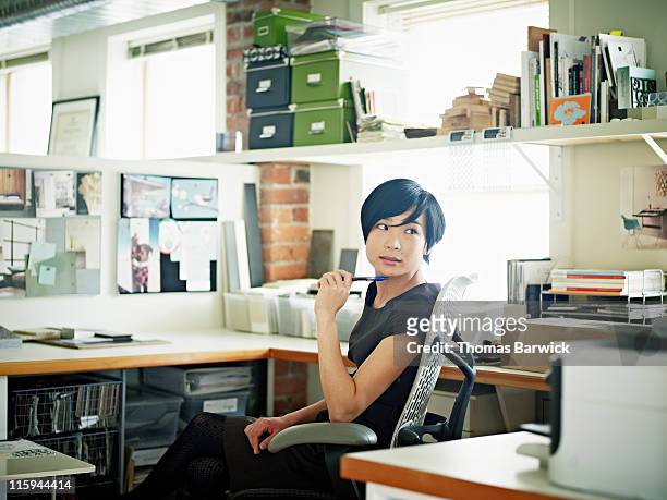 female designer at desk in office head turned - boss over shoulder stock-fotos und bilder