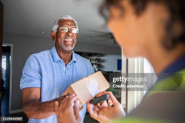 black woman consegna il pacco al cliente - consegna a domicilio foto e immagini stock