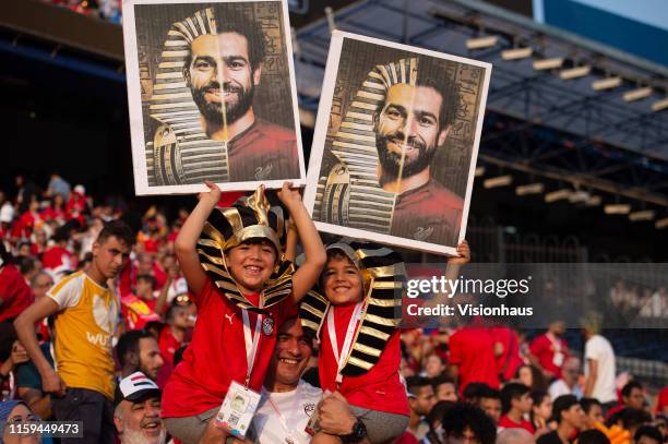 Father with his two sons dressed as pharaohs and holding photographs of Mohamed Salah during the 2019 Africa Cup of Nations Group A match between...