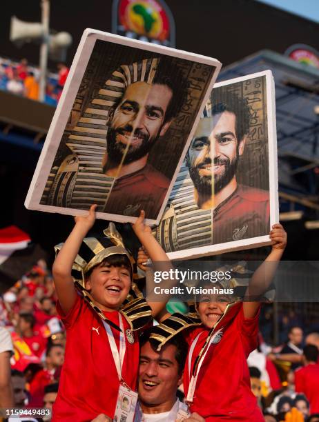 Father with his two sons dressed as pharaohs and holding photographs of Mohamed Salah during the 2019 Africa Cup of Nations Group A match between...