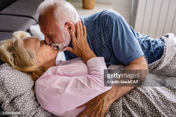 das alte seniorenpaar küssen sich im bett - man and woman kissing in bed stock-fotos und bilder