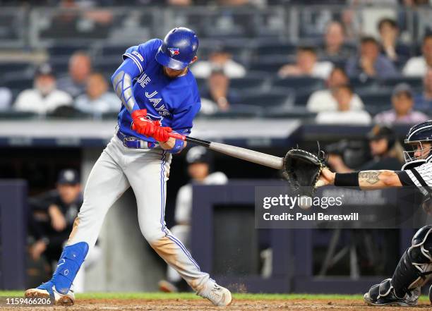 Cavan Biggio of the Toronto Blue Jays swings and his bat appears to hit the catcher's mitt of Gary Sanchez of the New York Yankees as Biggio was...