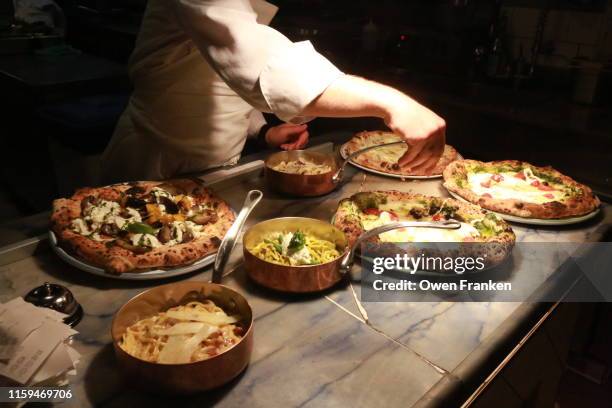 the final preparation of foods before being picked up by the servers, in an italian restaurant in paris - italiaans eten stockfoto's en -beelden