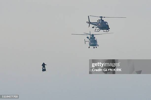 Franky Zapata moves with his jet-powered "Flyboard" next to helicopters as he arrives at St Margaret's Bay in Dover, on August 4 during his attempt...