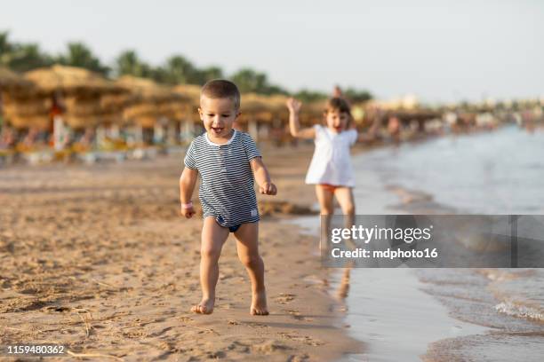 cute little baby girl and boy playing and running at a beach - egyptian family stock pictures, royalty-free photos & images