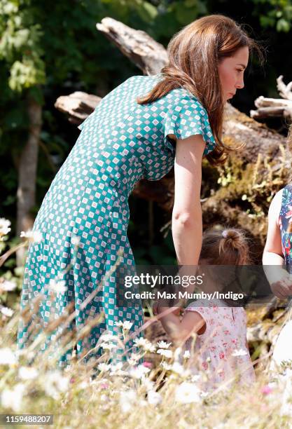 Catherine, Duchess of Cambridge holds hands with a young girl as she visits the RHS Hampton Court Palace Garden Festival to view the RHS 'Back to...