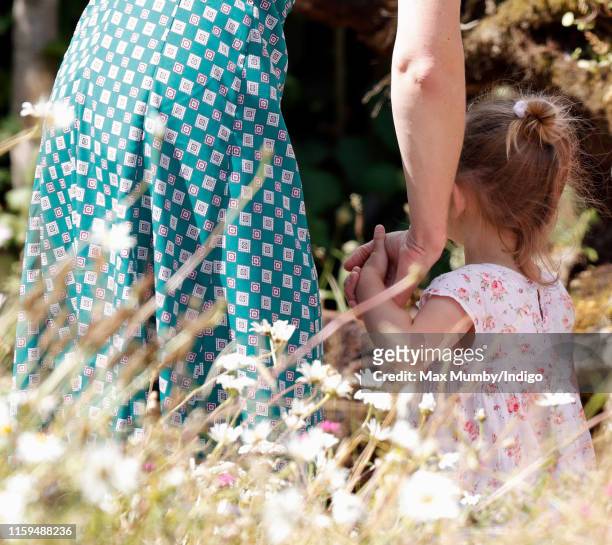 Catherine, Duchess of Cambridge holds hands with a young girl as she visits the RHS Hampton Court Palace Garden Festival to view the RHS 'Back to...