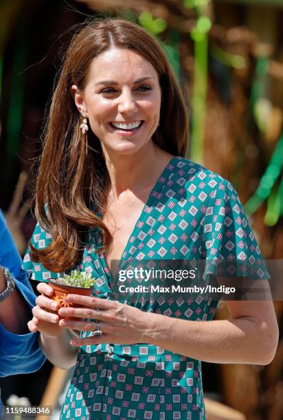 Catherine, Duchess of Cambridge holds a potted succulent plant as she visits the RHS Hampton Court Palace Garden Festival to view the RHS 'Back to...