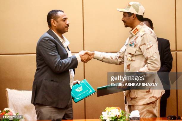 General Mohamed Hamdan Daglo , Sudan's deputy head of the Transitional Military Council, and protest leader Ahmed Rabie shake hands after signing the...