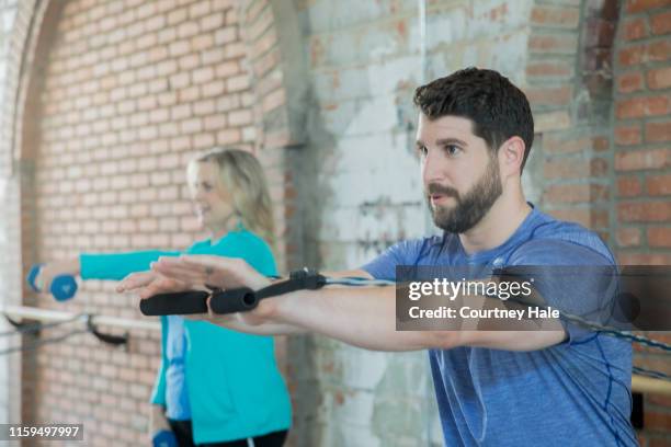 mann mit trainingsbändern zur stärkung der muskeln während der physiotherapie-trainingseinheit - sportmedizin happy stock-fotos und bilder