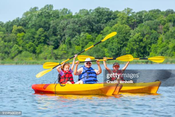 grandma & two granddaughters in kayaks on lake - family red canoe stock pictures, royalty-free photos & images