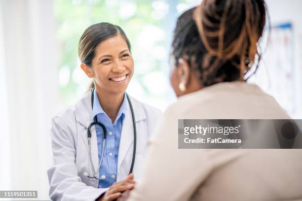 older woman in medical consultation with her doctor - female doctor stock pictures, royalty-free photos & images