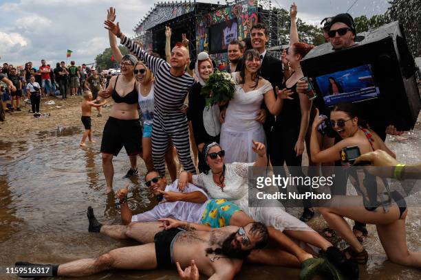 Group of people poses for a picture in a mud in front of the main stage of the 25th PolnRock music festival in Kostrzyn at Odra, Poland on August 3,...