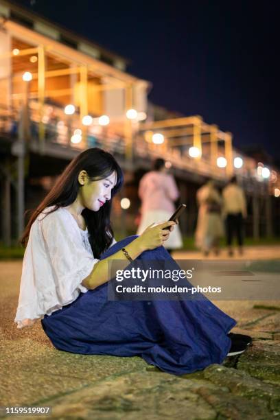 young asian woman traveling in kyoto with a mobile phone - kamo river stock pictures, royalty-free photos & images