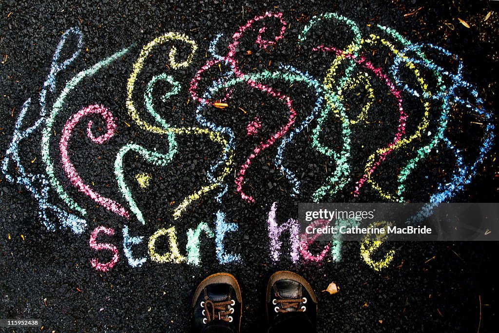 "Start here" drawn in chalk beside feet