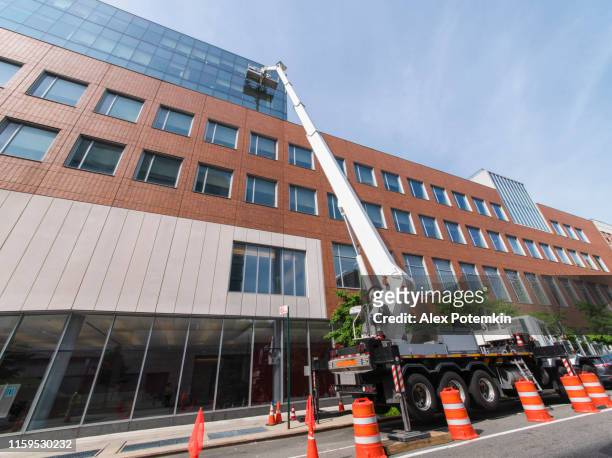 high-altitude work. team of blue-collar workers working on the office building glass facade using the lifting platform. - facade cleaning stock pictures, royalty-free photos & images