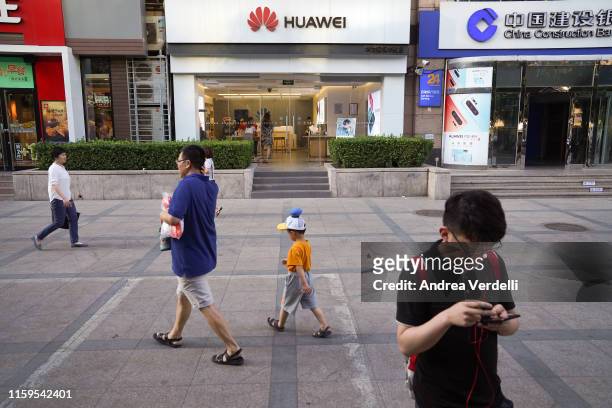 People walk past a Huawei store on July 1, 2019 in Chaoyang Outer Street, Chaoyang District, Beijing.