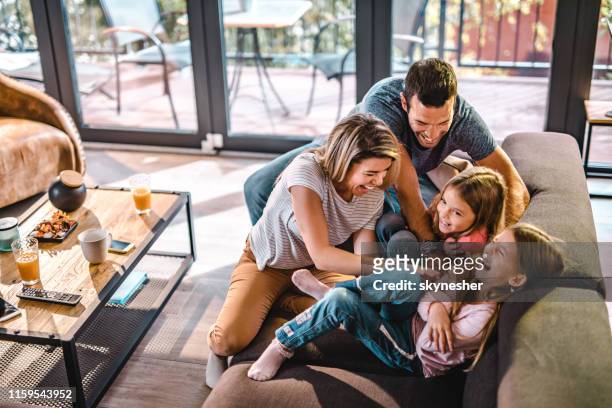 above view of playful parents tickling their daughters at home. - family stock pictures, royalty-free photos & images