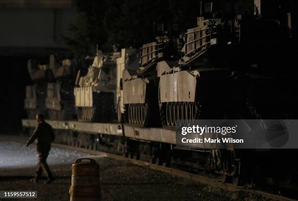 Two M1A1 Abrams tanks and other military vehicles sit guarded on rail cars at a railyard in Washington, DC. President Trump has asked the Pentagon...