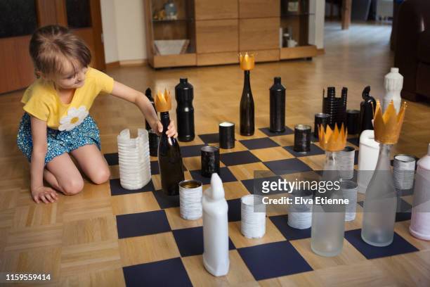 child (6-7) playing chess with recycled tin cans, plastic and glass bottles - chess board without photos et images de collection