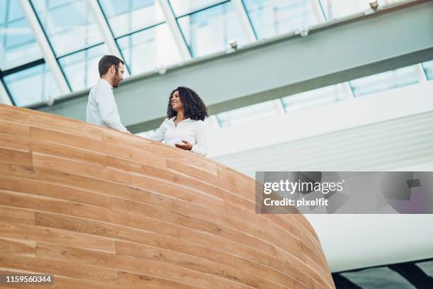 couple of business persons talking in modern office space - businessman and businesswoman shaking hands stock pictures, royalty-free photos & images