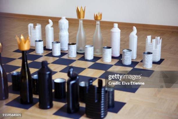 recycled tin cans, plastic and glass bottles upcycled to make chess pieces positioned on a cardboard chess board - chess board without photos et images de collection