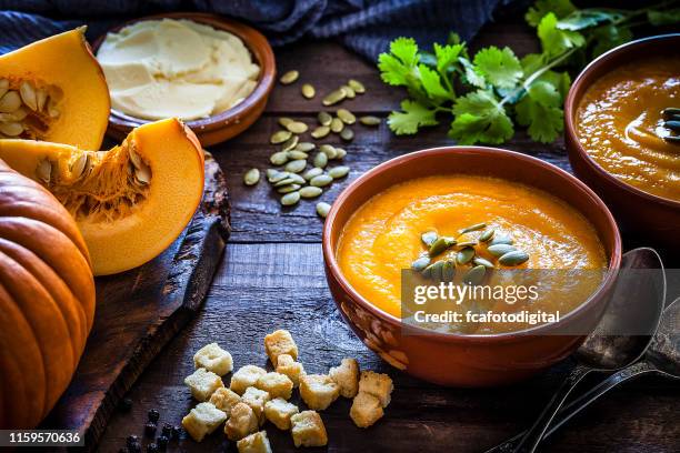 pumpkin soup with ingredients on rustic wooden table - pumpkin soup stock pictures, royalty-free photos & images