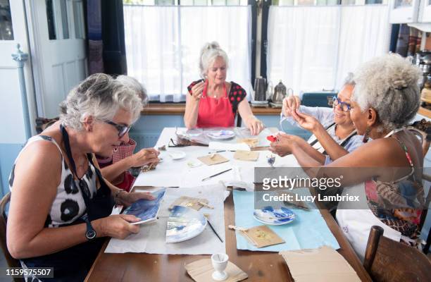 Mixed group of senior women at a new kintsugi workshop: fixing broken ceramics with golden glue