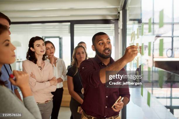 directing his team along his plan for success - glass business man stock pictures, royalty-free photos & images