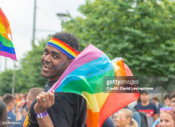 proud gay man during pride parade - regenbogenfahne stock-fotos und bilder
