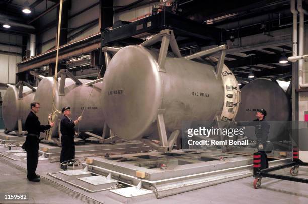Workers handle special containers filled with M-55 rockets armed with sarin gas, a nerve agent, at an incinerator June 12, 1995 at the Tooele Army...