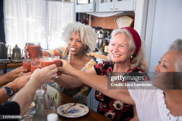 Mixed group of women at a vegan lunch toasting with a glass of gazpacho