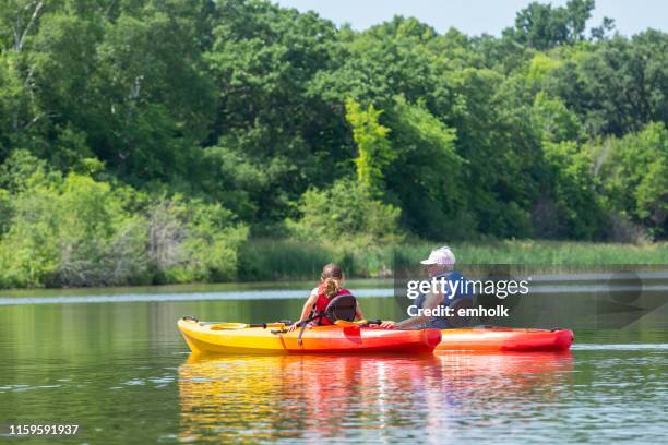 girl & grandma relaxing in kayaks on summer day - family red canoe stock pictures, royalty-free photos & images