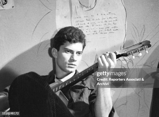 Italian singer-songwriter and actor Luigi Tenco playing guitar on the set of the film A Girl... And a Million. Italy, 1962