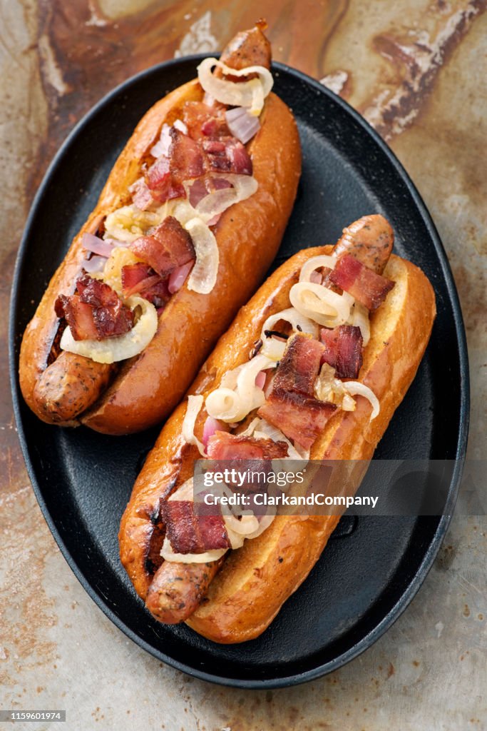 Artisan hot dogs in a brioche bun with bacon and onion.