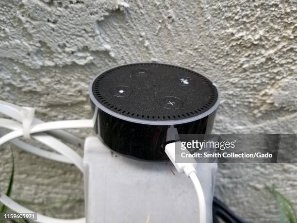 Amazon Echo Dot smart speaker, using the Alexa voice assistant service, being used as an outdoor speaker in a garden setting in a smart home in San...