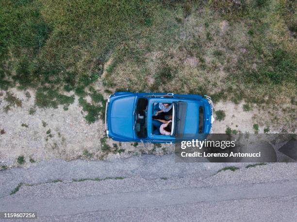 overhead view of friends talking inside car by roadside - car sunroof stockfoto's en -beelden